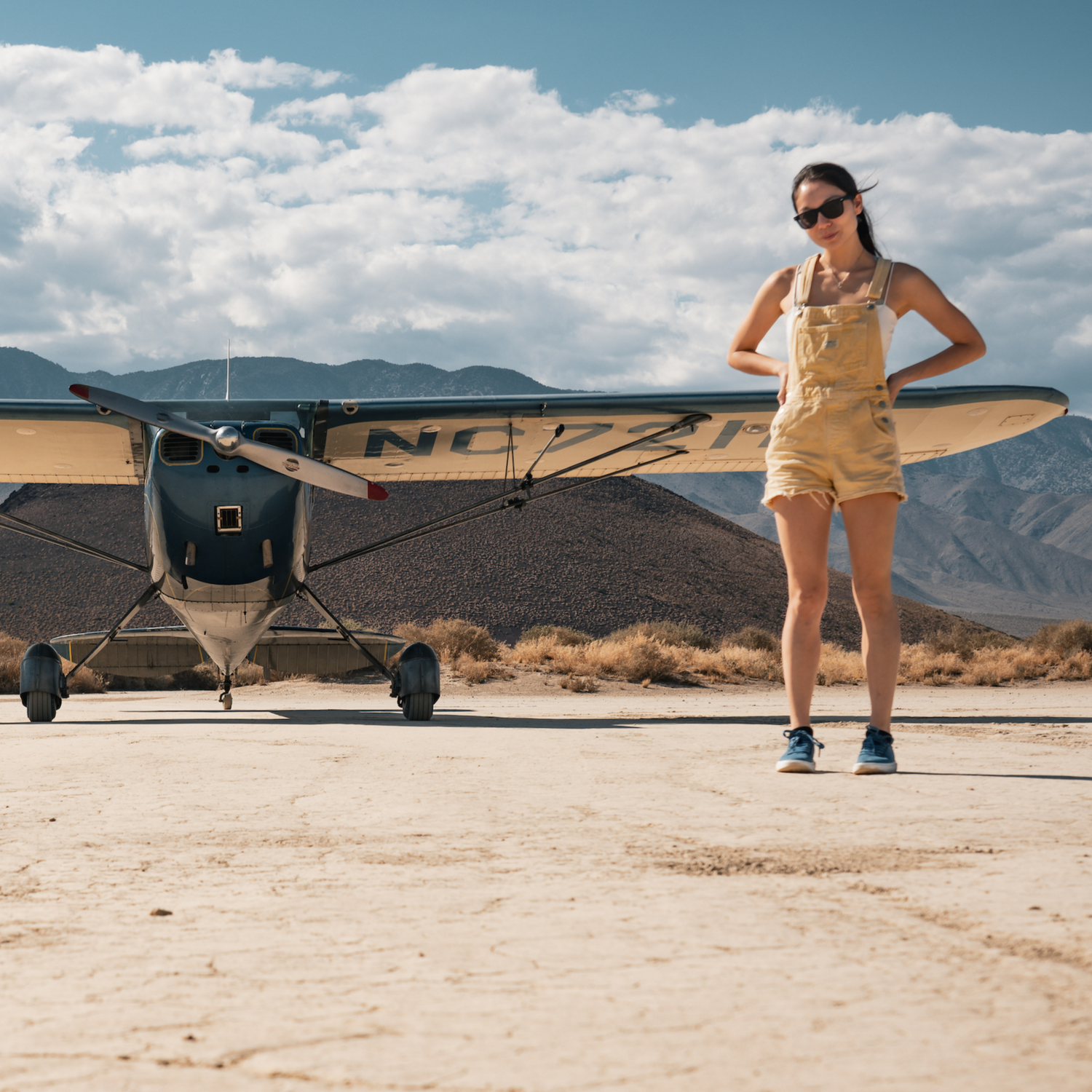 Xyla Foxlin standing next to a small Cessna airplane on a desert airstrip with mountains in the background